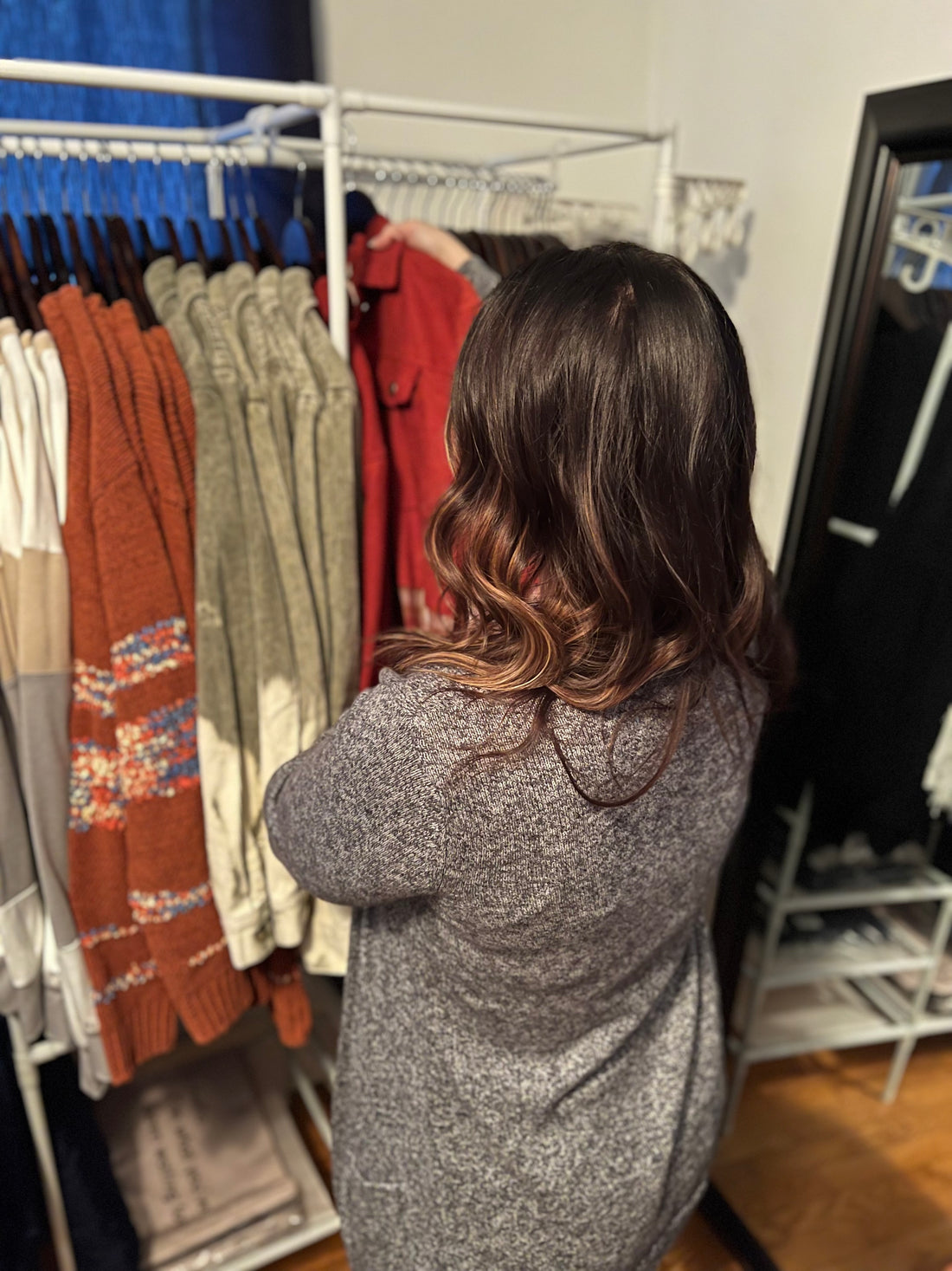 A woman looking through a rack of clothes.