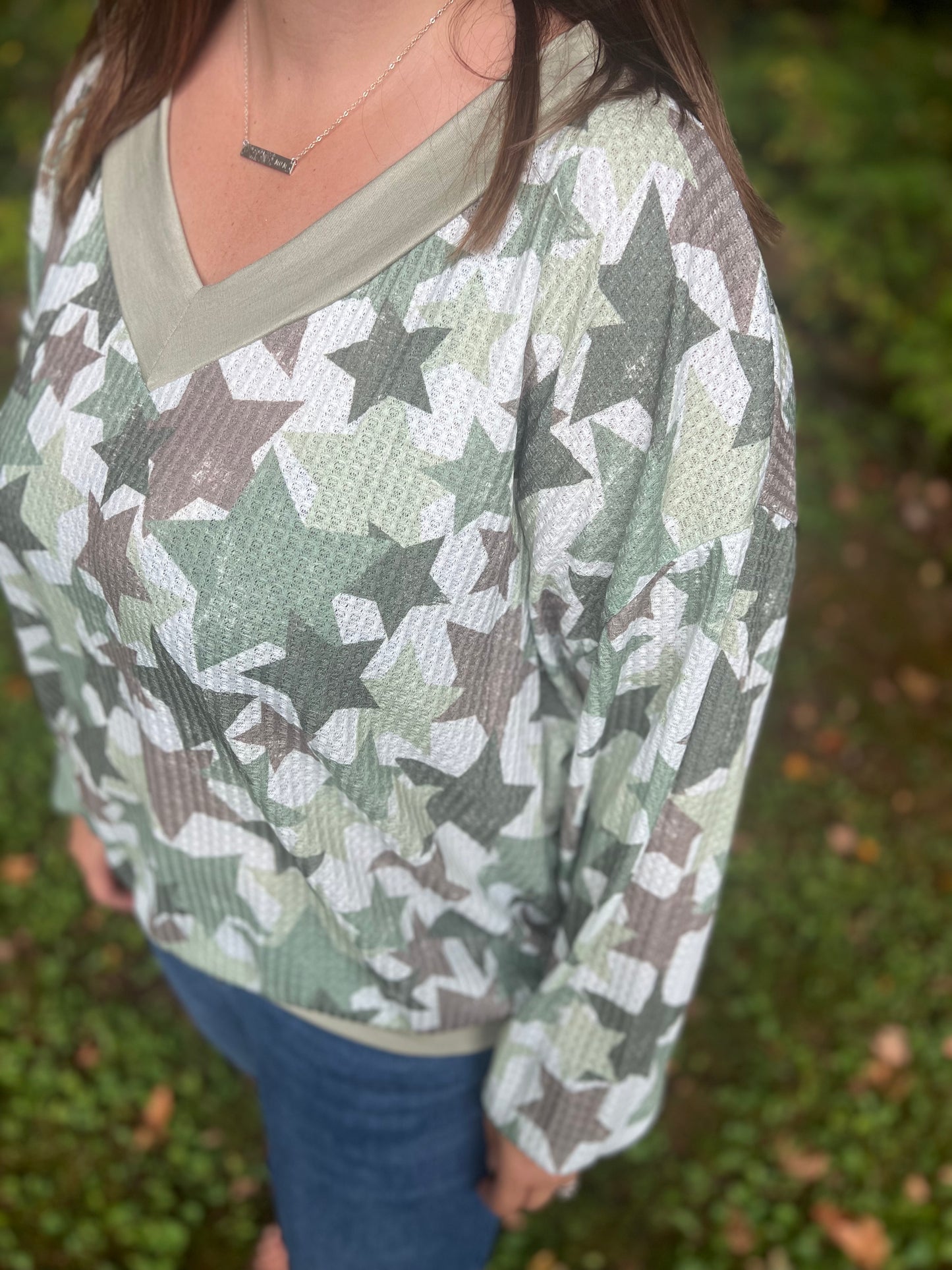 Mid-size women in her thirties modeling a green star camo-like waffle long sleeve shirt