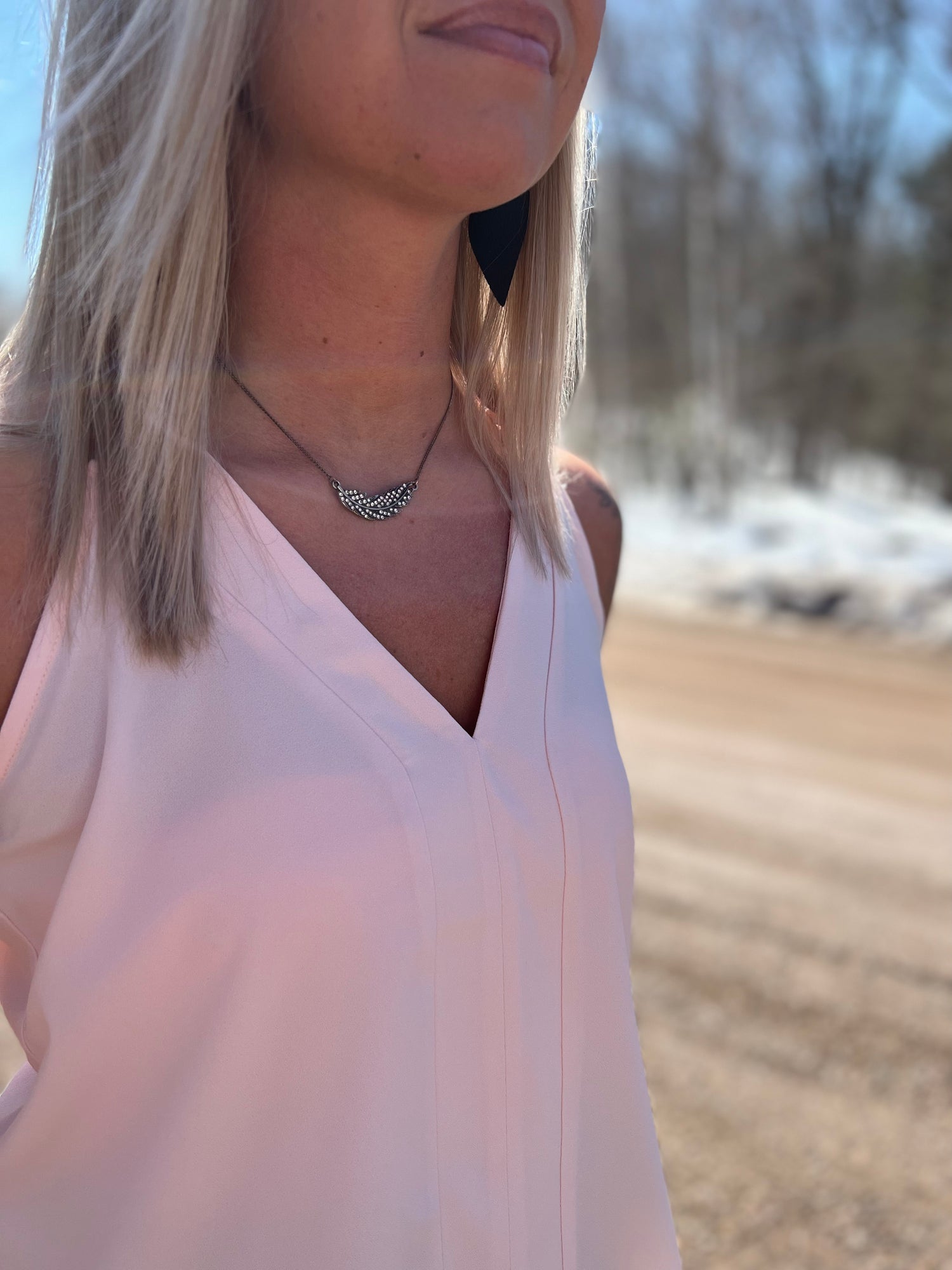 A woman wearing a blush pink tank top. 