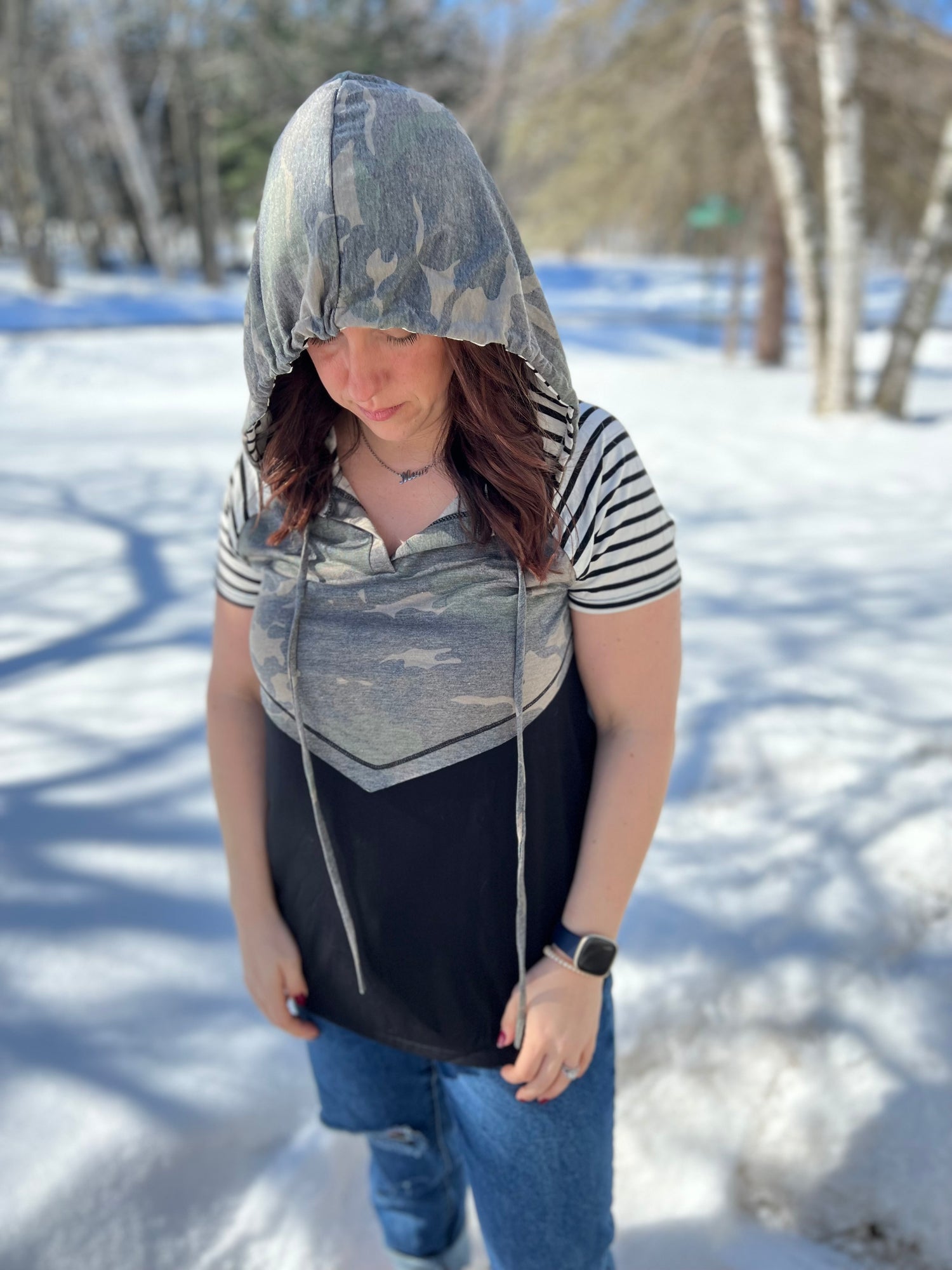 A women wearing a camo print solid and stripe mixed t-shirt with hoodie. 