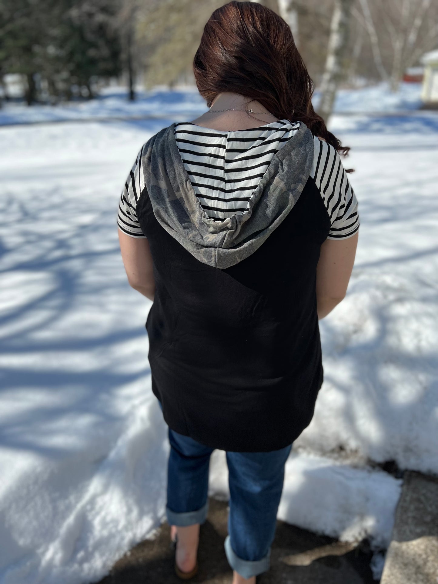 A women wearing a camo print solid and stripe mixed t-shirt with hoodie. 