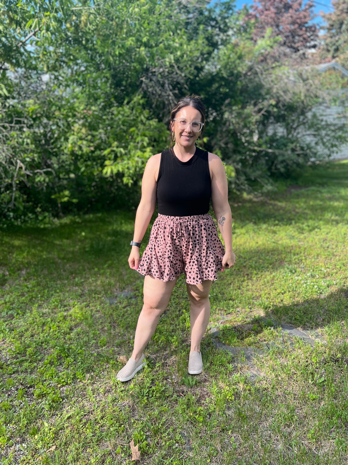 A woman wear black polka dot on tan flared shorts, almost leopard print. 